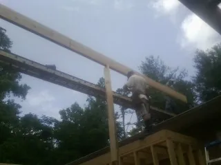 Carpenter setting a ridge beam over a new addition frame — Ice Dam Removal by Roofing Brothers in Post