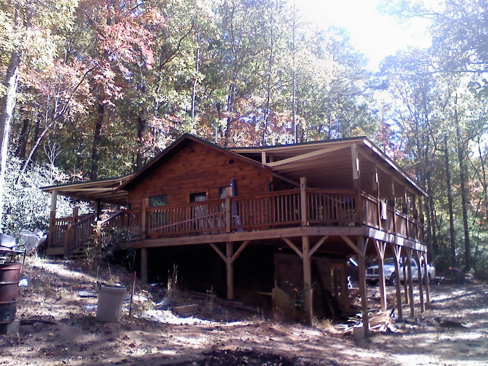 Log cabin with a wraparound porch and metal roof in the fall in Post