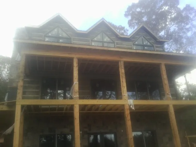Dormers and porch framing on a large log home under construction — Roof Coating work by our crew in Post