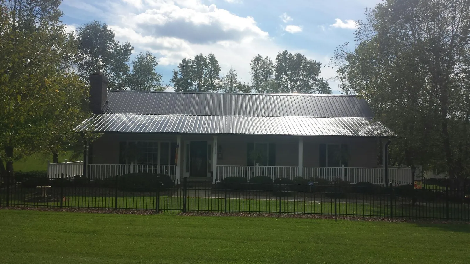 Gray metal roof on a brick ranch with a full width front porch — Gutter Guard Installation work by our crew in Post