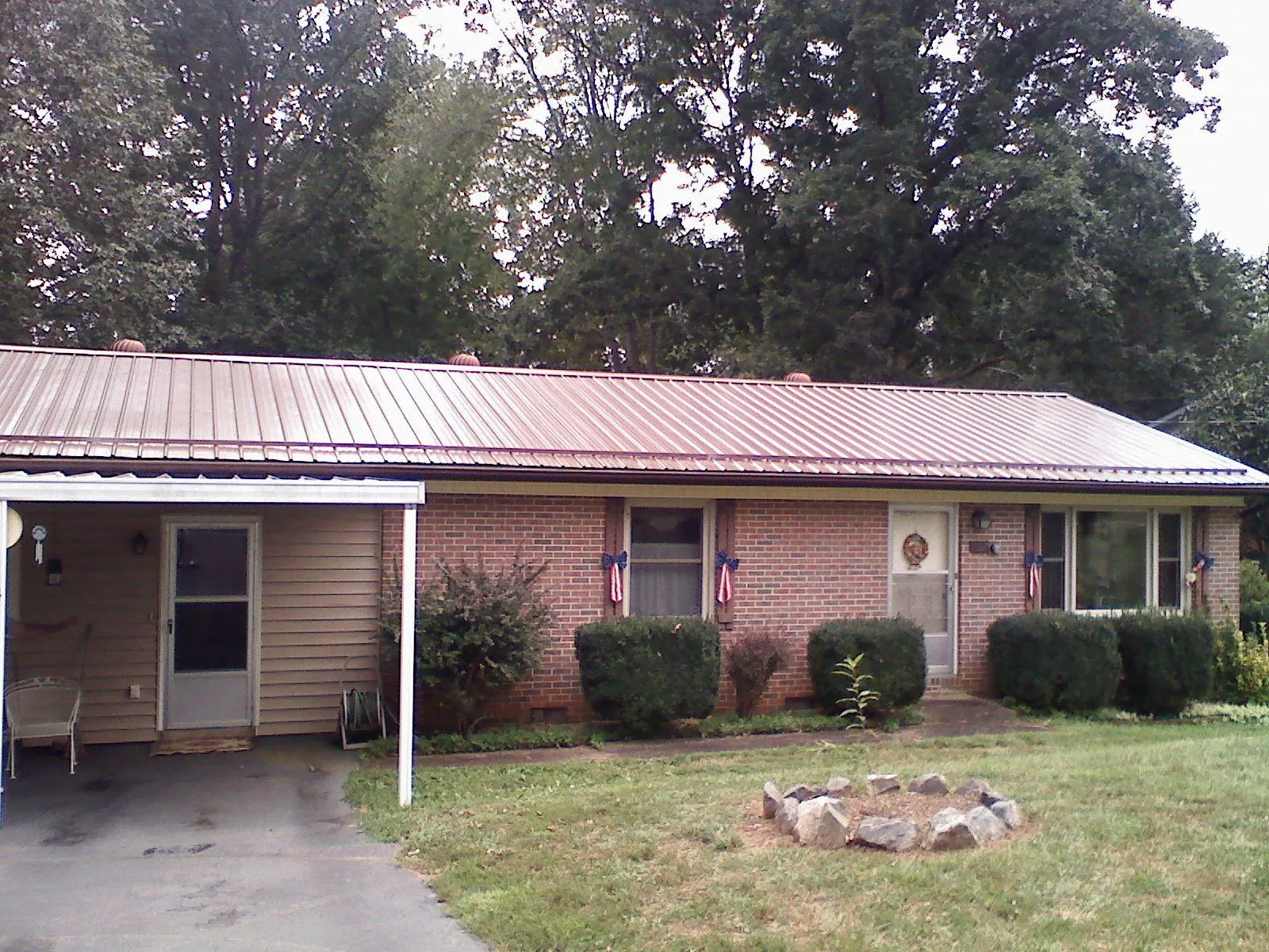 Bronze metal roof and carport on a brick ranch home — Roof Repair work by our crew in Post
